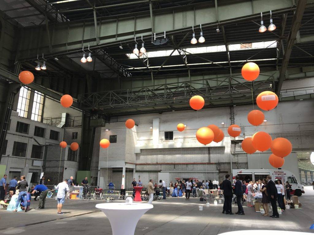 Beispielfoto einer Messehalle mit Menschen und Luftballons